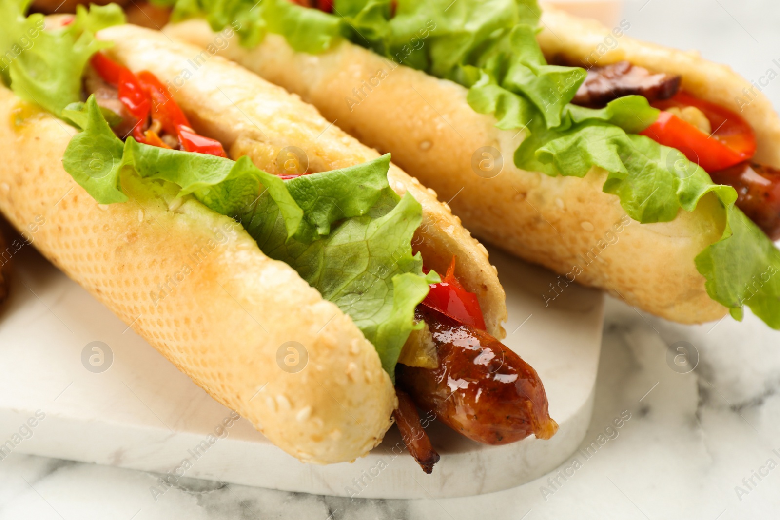 Photo of Tasty hot dogs on white marble table, closeup. Fast food