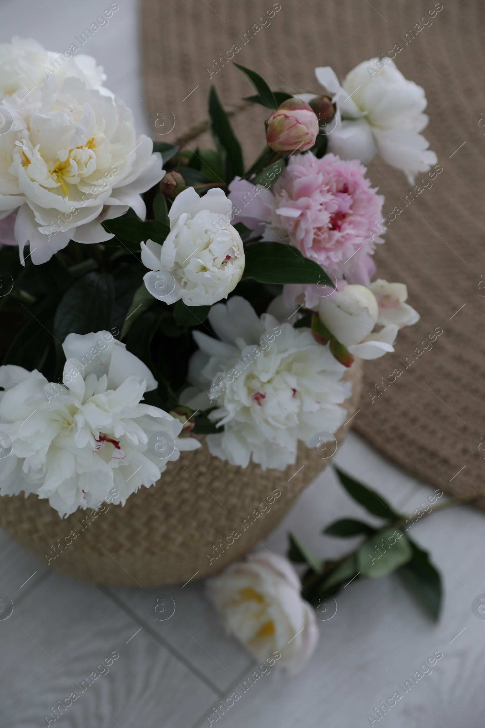 Photo of Bouquet of beautiful peony flowers in basket on floor