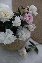 Bouquet of beautiful peony flowers in basket on floor