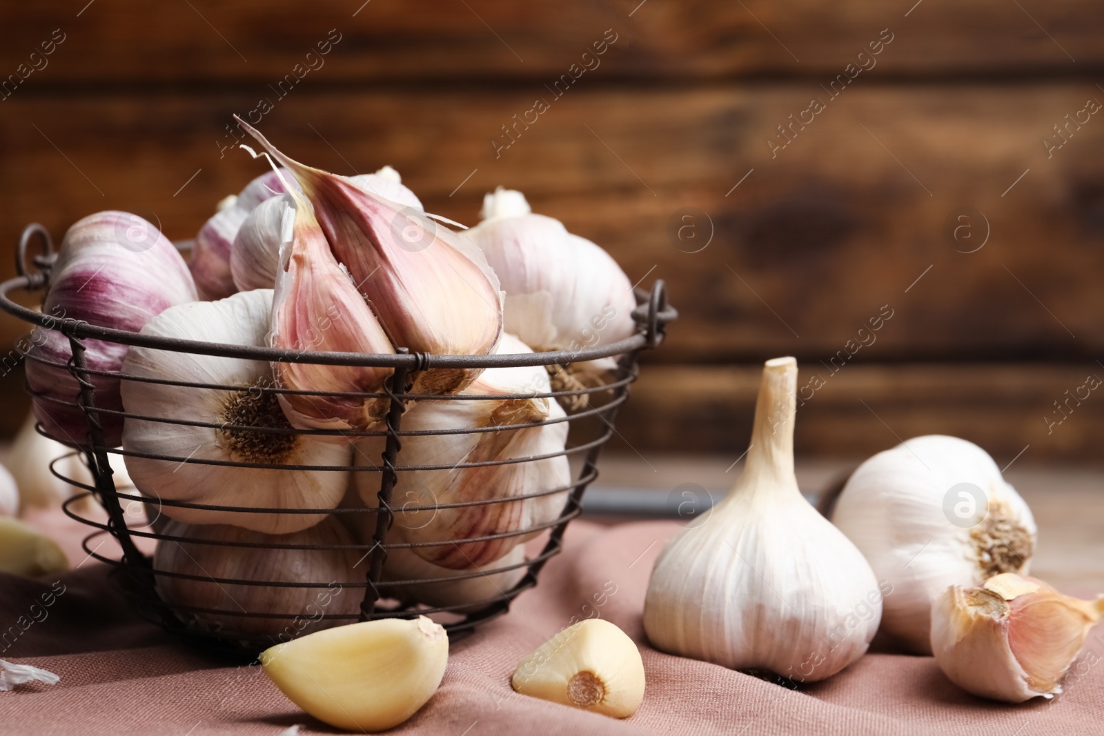 Photo of Fresh organic garlic in basket on table