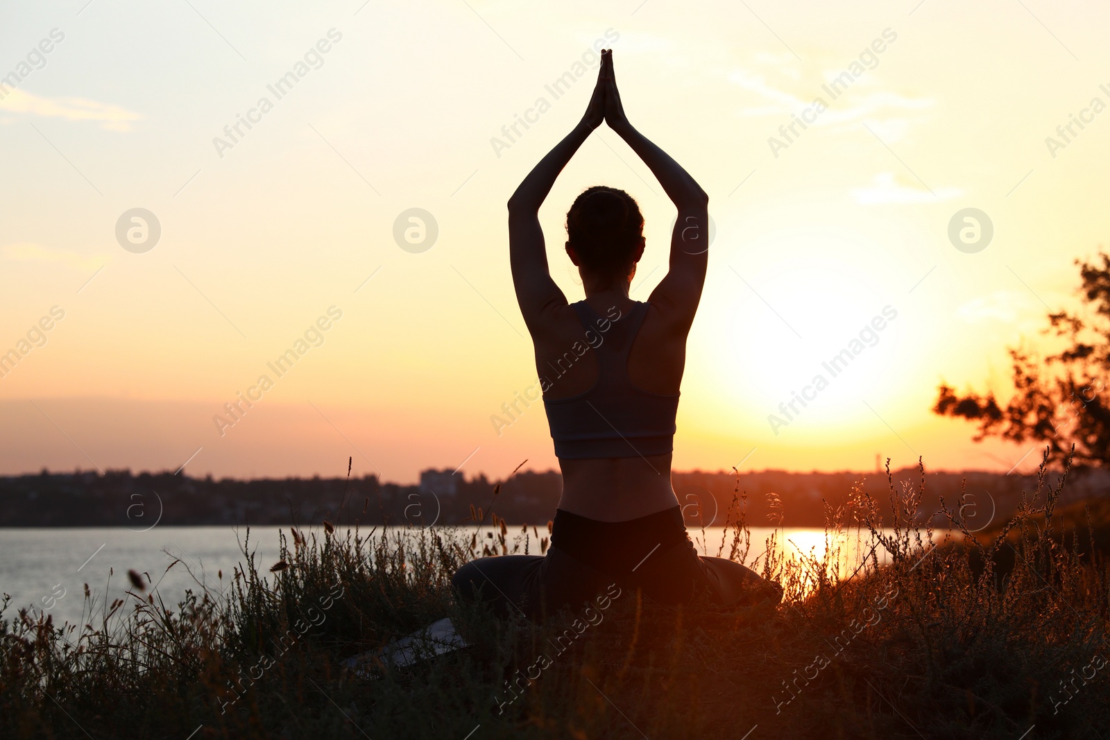 Photo of Young woman practicing yoga outdoors on sunset. Zen meditation