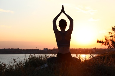 Photo of Young woman practicing yoga outdoors on sunset. Zen meditation