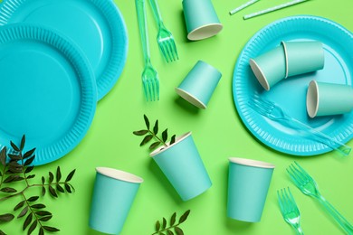 Photo of Flat lay composition with disposable tableware on green background