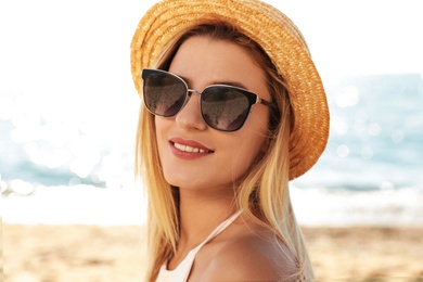 Beautiful woman wearing sunglasses at beach on sunny day