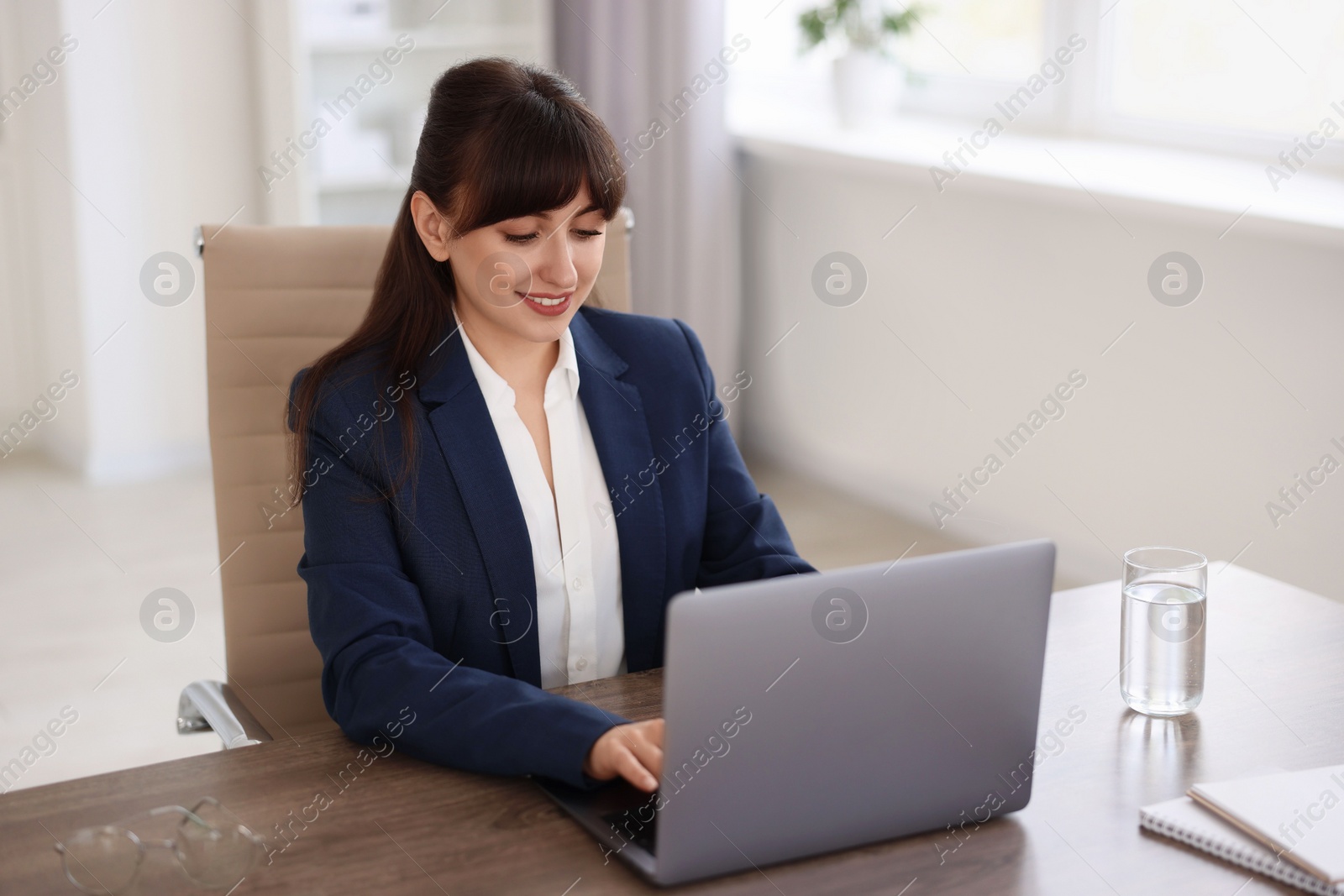 Photo of Woman watching webinar at wooden table in office