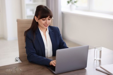 Photo of Woman watching webinar at wooden table in office