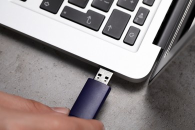 Photo of Man connecting usb flash drive to laptop at grey table, above view