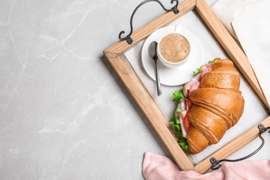 Photo of Tasty croissant sandwich and coffee on light grey marble table, flat lay. Space for text