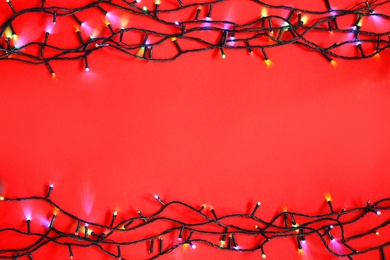 Glowing Christmas lights on color background, top view