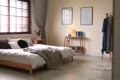 Photo of Modern room interior with comfortable double bed and window blinds