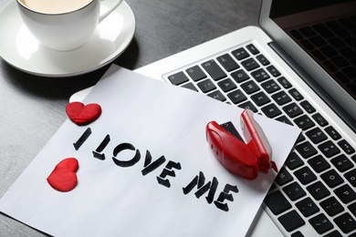 Photo of Paper with phrase I Love Me, laptop, red hearts and stapler on grey desk