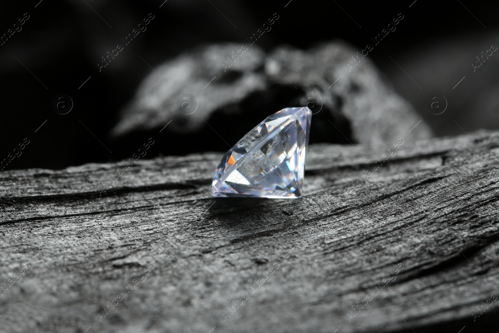 Photo of Beautiful shiny diamond on coal, closeup view