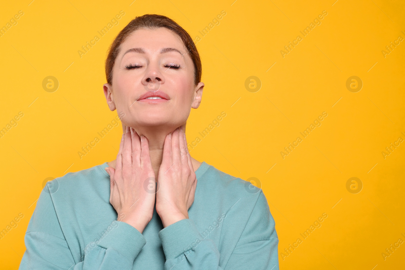 Photo of Woman suffering from sore throat on orange background. Space for text