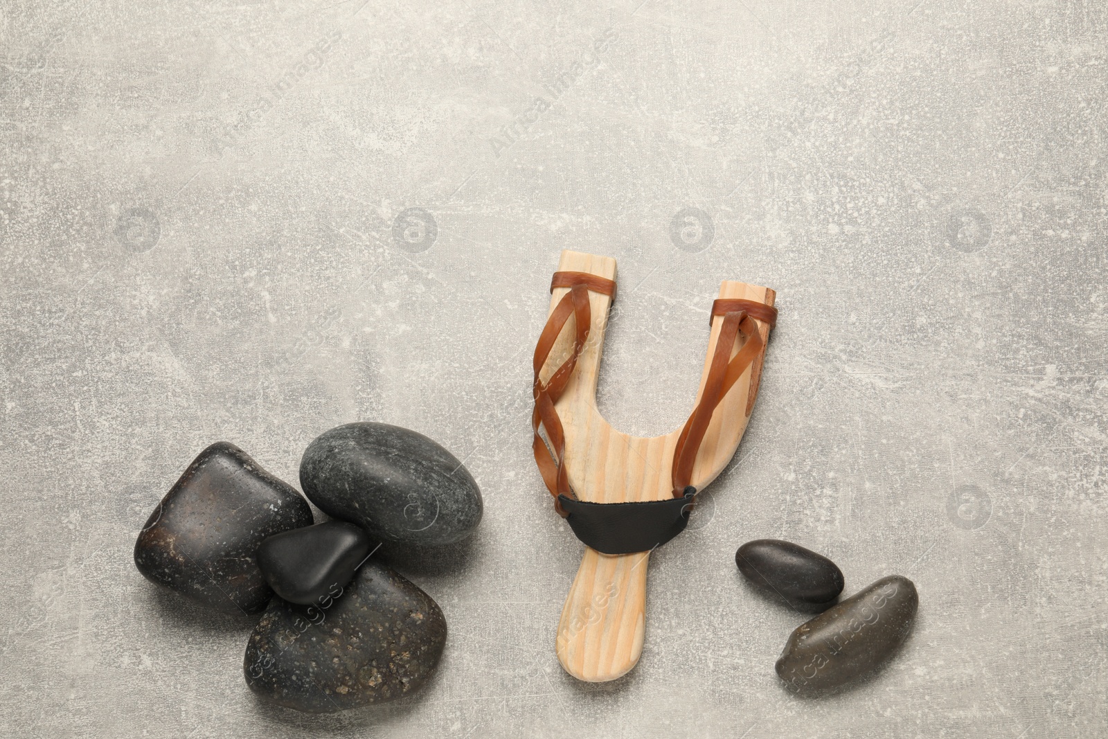 Photo of Slingshot with stones on light grey background, flat lay