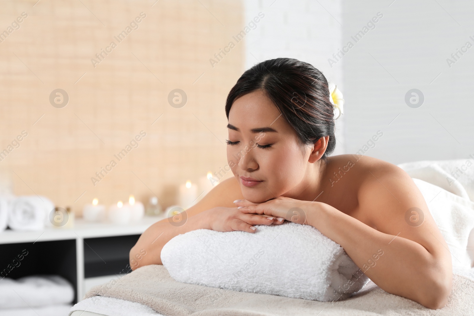 Photo of Beautiful Asian woman lying on massage table in spa salon. Space for text