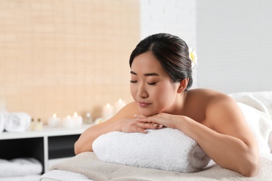 Photo of Beautiful Asian woman lying on massage table in spa salon. Space for text