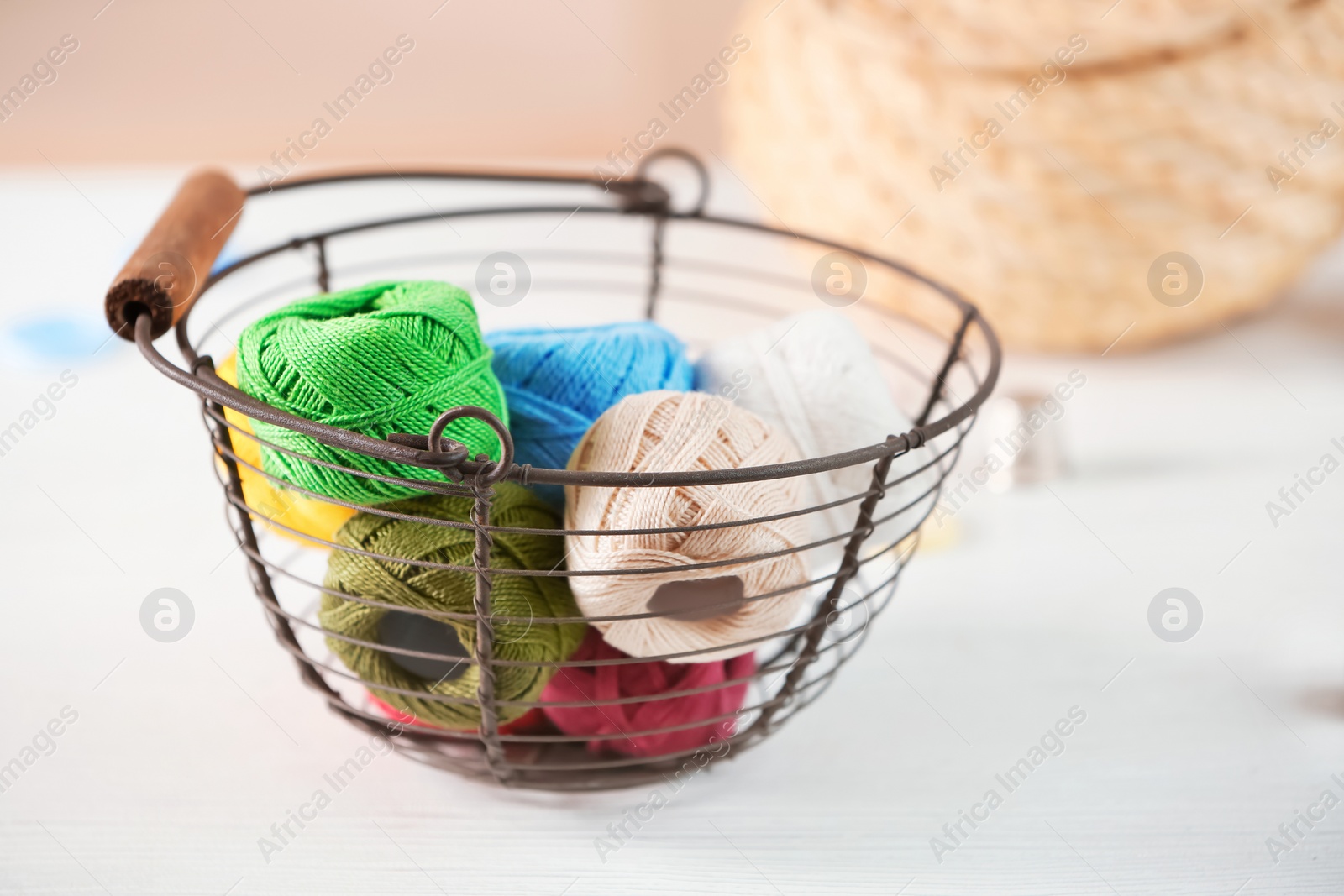 Photo of Metal basket with knitting threads on table