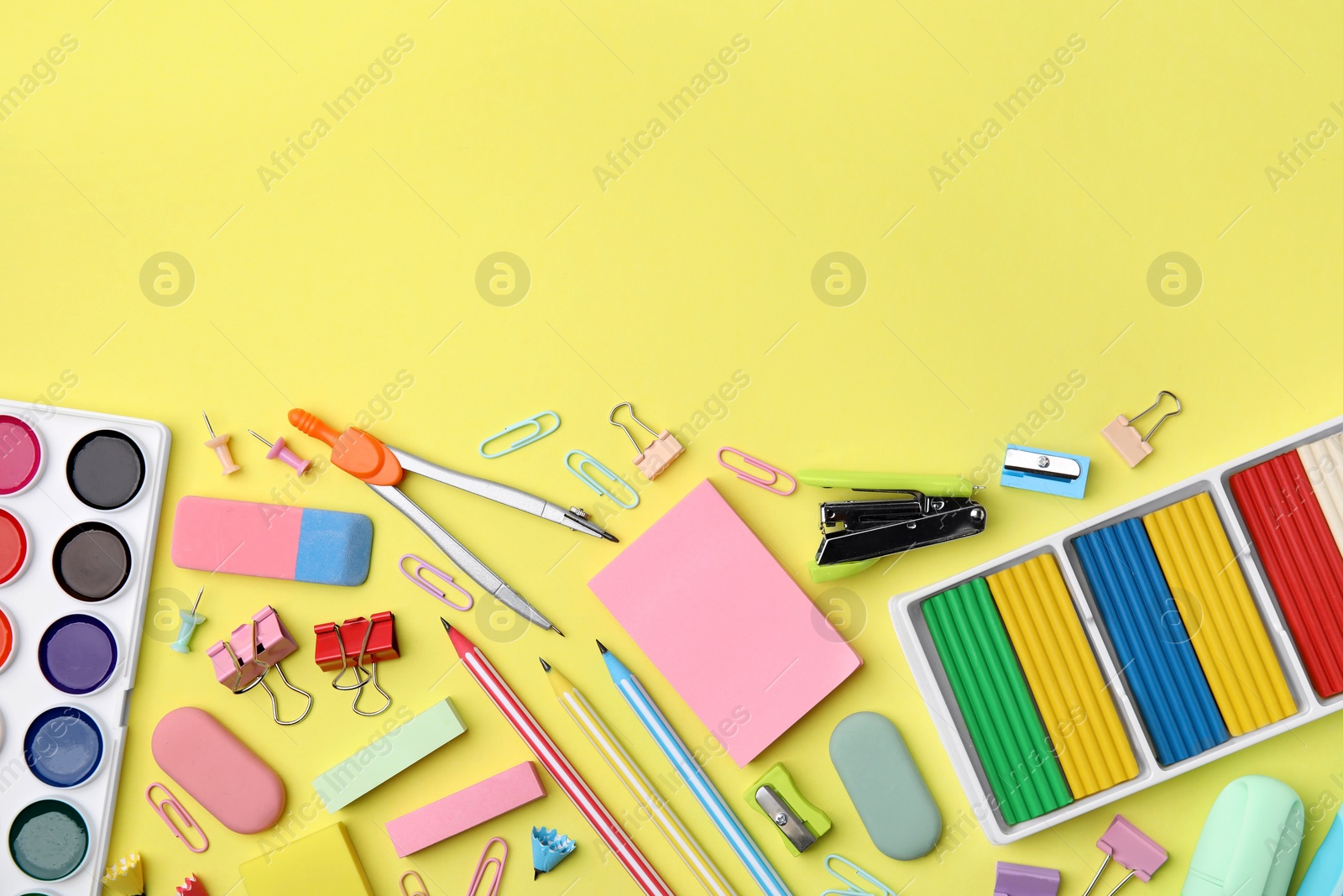 Photo of Flat lay composition with different school stationery on pale yellow background, space for text. Back to school