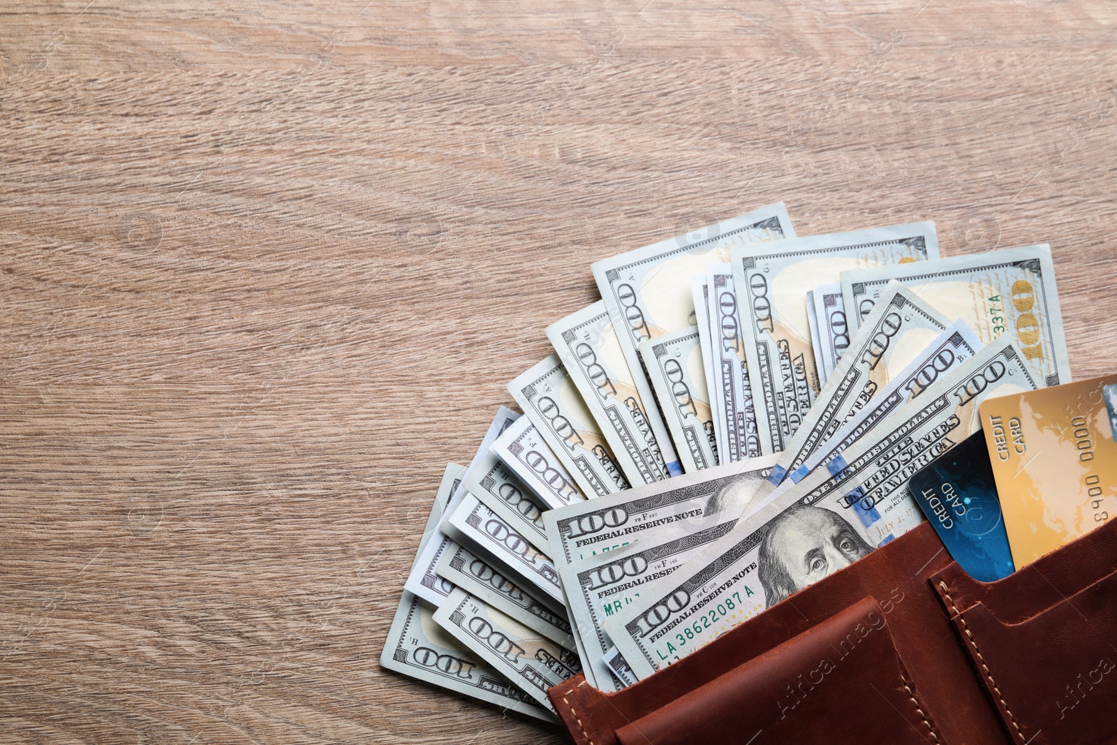 Photo of Many dollar banknotes with wallet and credit cards on wooden table, flat lay. Space for text