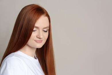 Photo of Candid portrait of happy young woman with charming smile and gorgeous red hair on beige background, space for text