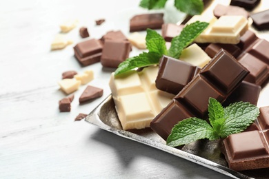 Photo of Different kinds of chocolate with mint on light table