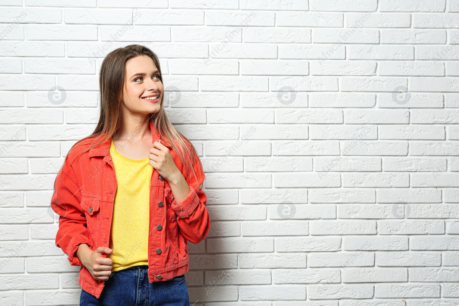 Photo of Young woman wearing blank t-shirt near white brick wall. Mockup for design