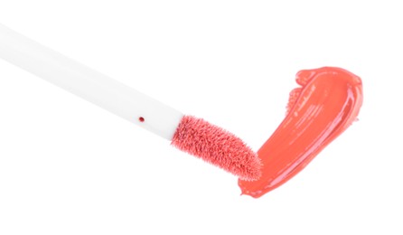Photo of Stroke of color lip gloss and applicator isolated on white, top view