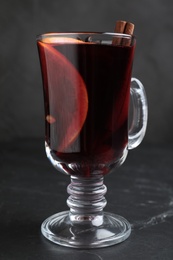 Photo of Aromatic mulled wine on black table, closeup