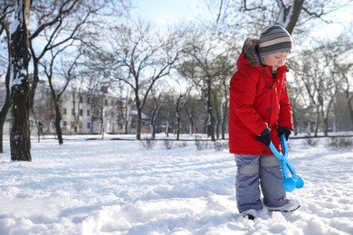 Photo of Cute little boy playing with snowball maker in park on sunny winter day. Space for text