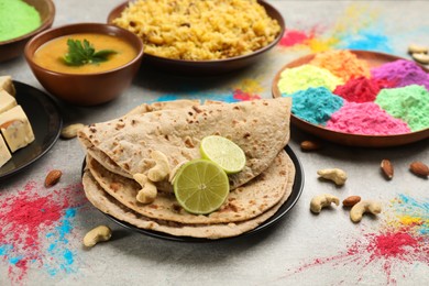 Photo of Traditional Indian food and color powders on grey table. Holi festival celebration