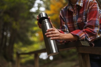 Photo of Woman with metallic thermos outdoors, closeup. Space for text