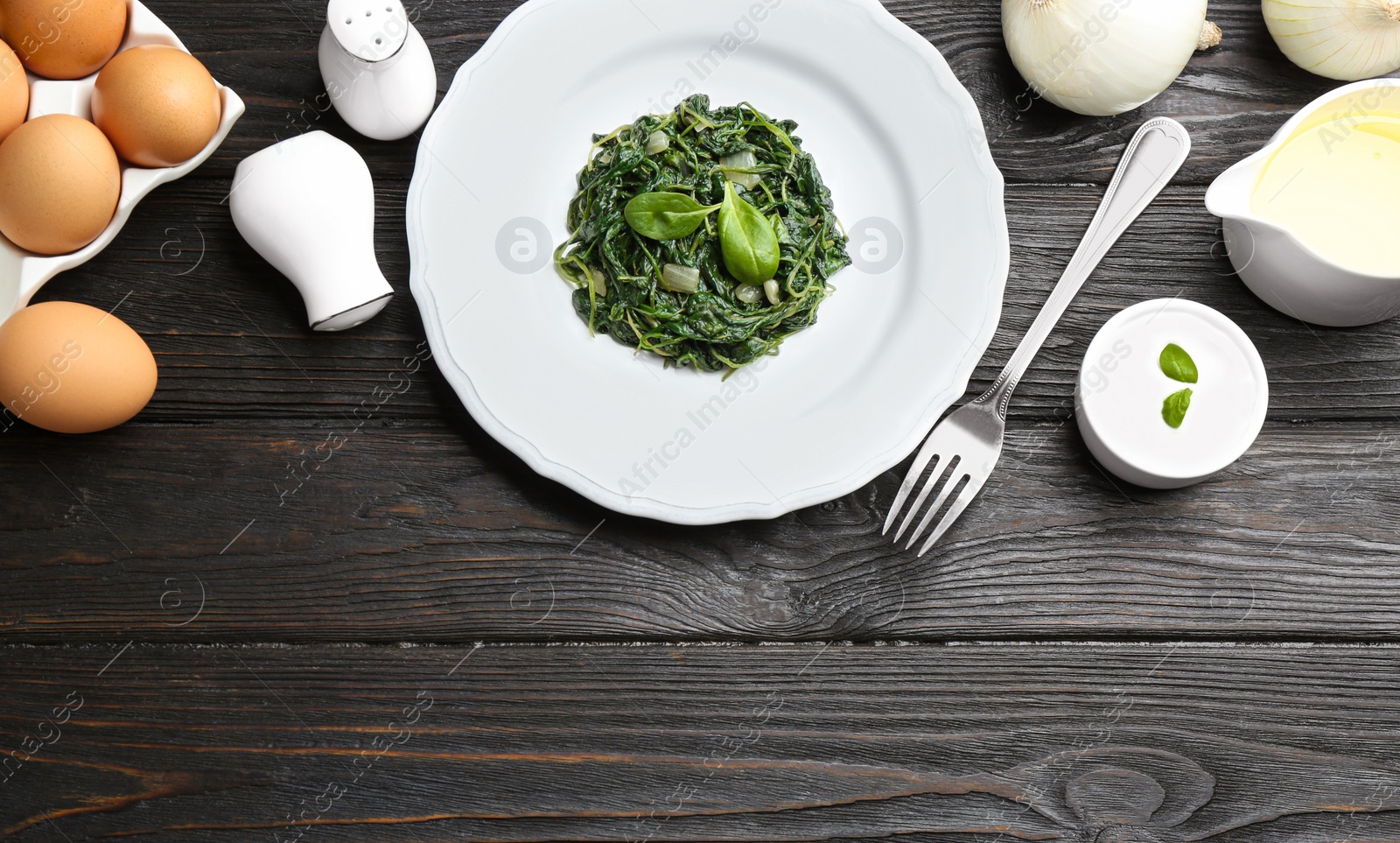 Photo of Flat lay composition with cooked spinach on black wooden table. Healthy food