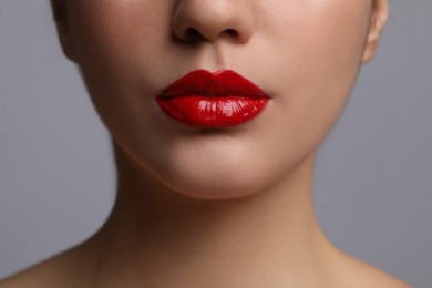 Photo of Closeup view of woman with beautiful full lips on grey background