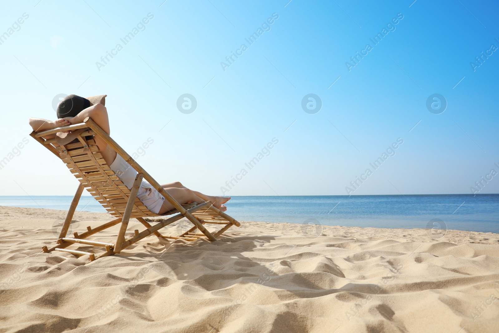 Photo of Young woman relaxing in deck chair on sandy beach