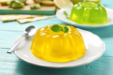 Photo of Plate of tasty fruit jelly and mint on blue wooden table, closeup