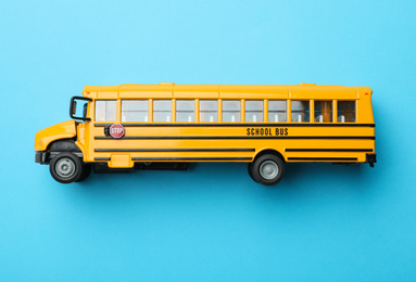 Photo of Yellow school bus on light blue background, top view. Transport for students