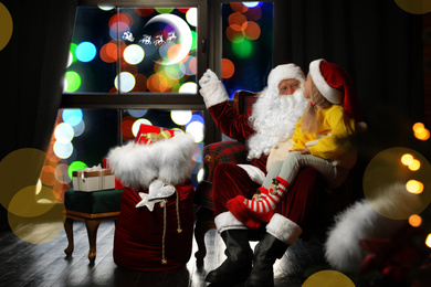 Photo of Santa Claus and little girl near window indoors. Christmas time