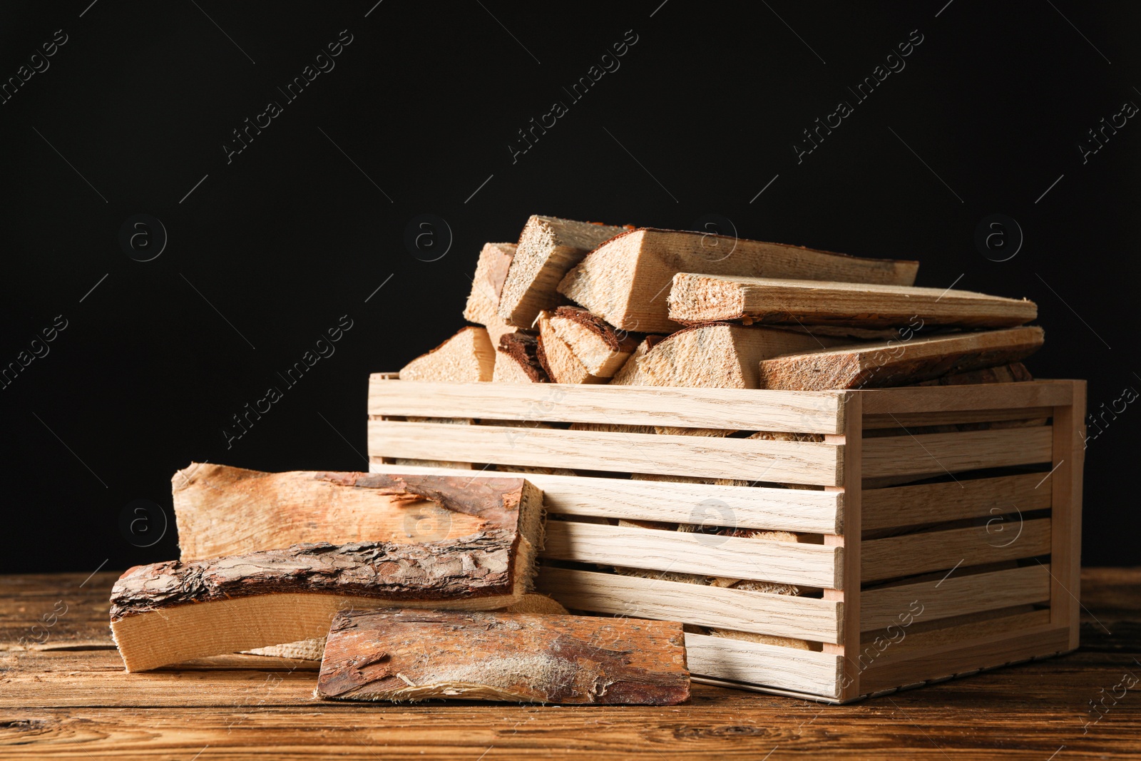 Photo of Cut firewood on table against black background