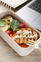 Healthy products high in vegetable fats near laptop on wooden table, closeup