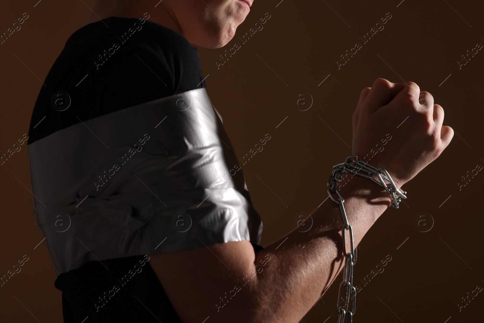 Photo of Little boy with tied arms taken hostage on dark background, closeup