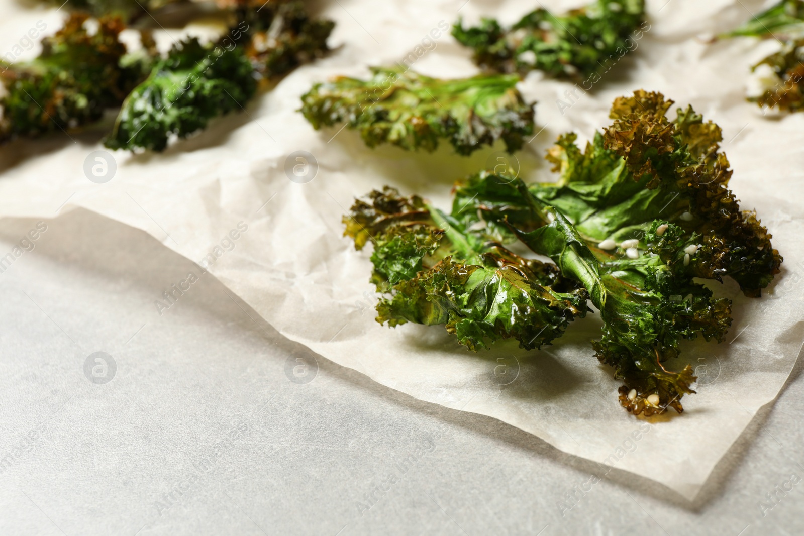 Photo of Tasty baked kale chips on grey table, closeup