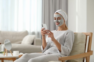 Photo of Young woman with face mask using smartphone at home, space for text. Spa treatments