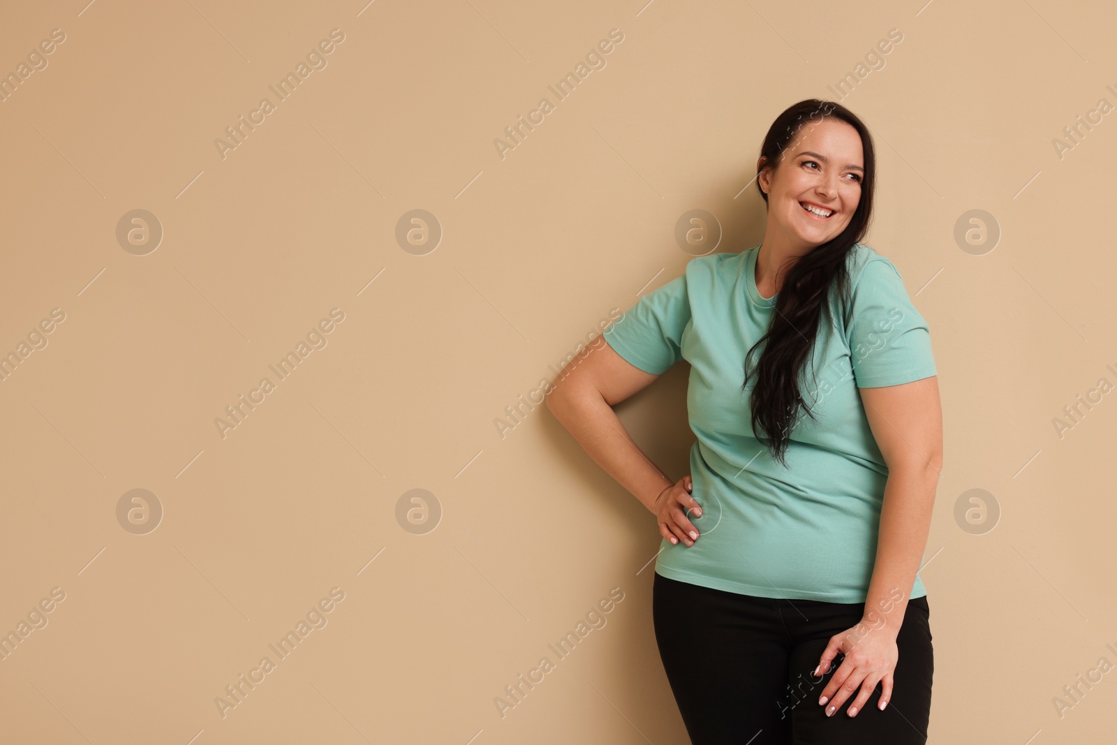 Photo of Beautiful overweight woman with charming smile on beige background. Space for text