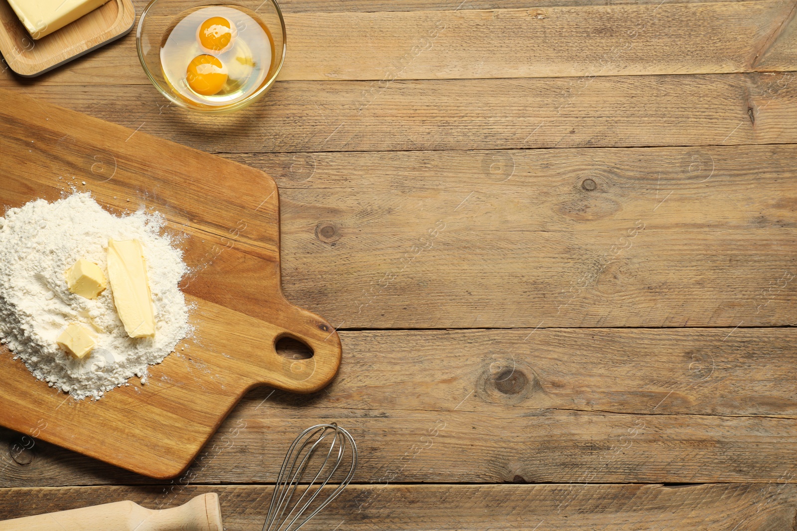 Photo of Board with fresh butter and flour on wooden table, flat lay. Space for text