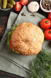 Delicious vegetarian burger and ingredients on wooden table, top view