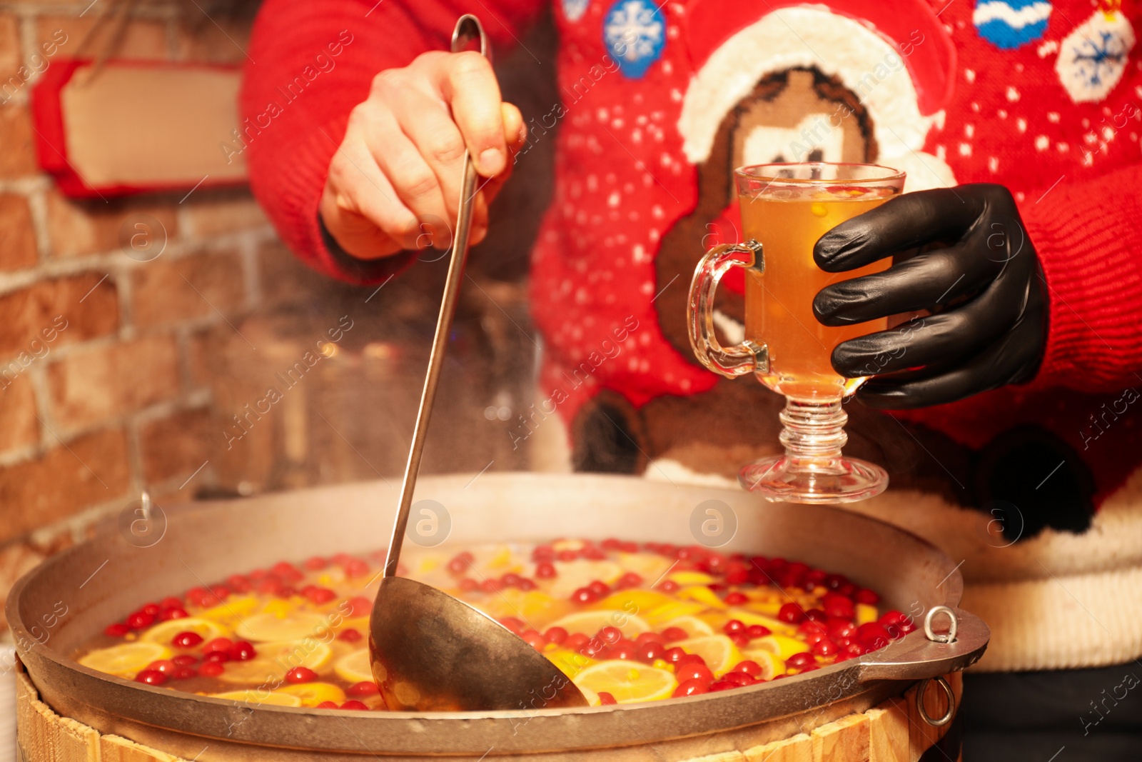 Photo of Seller filling cup with tasty mulled wine at winter fair, closeup