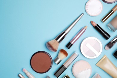 Face powder and other decorative cosmetic products on light blue background, flat lay. Space for text