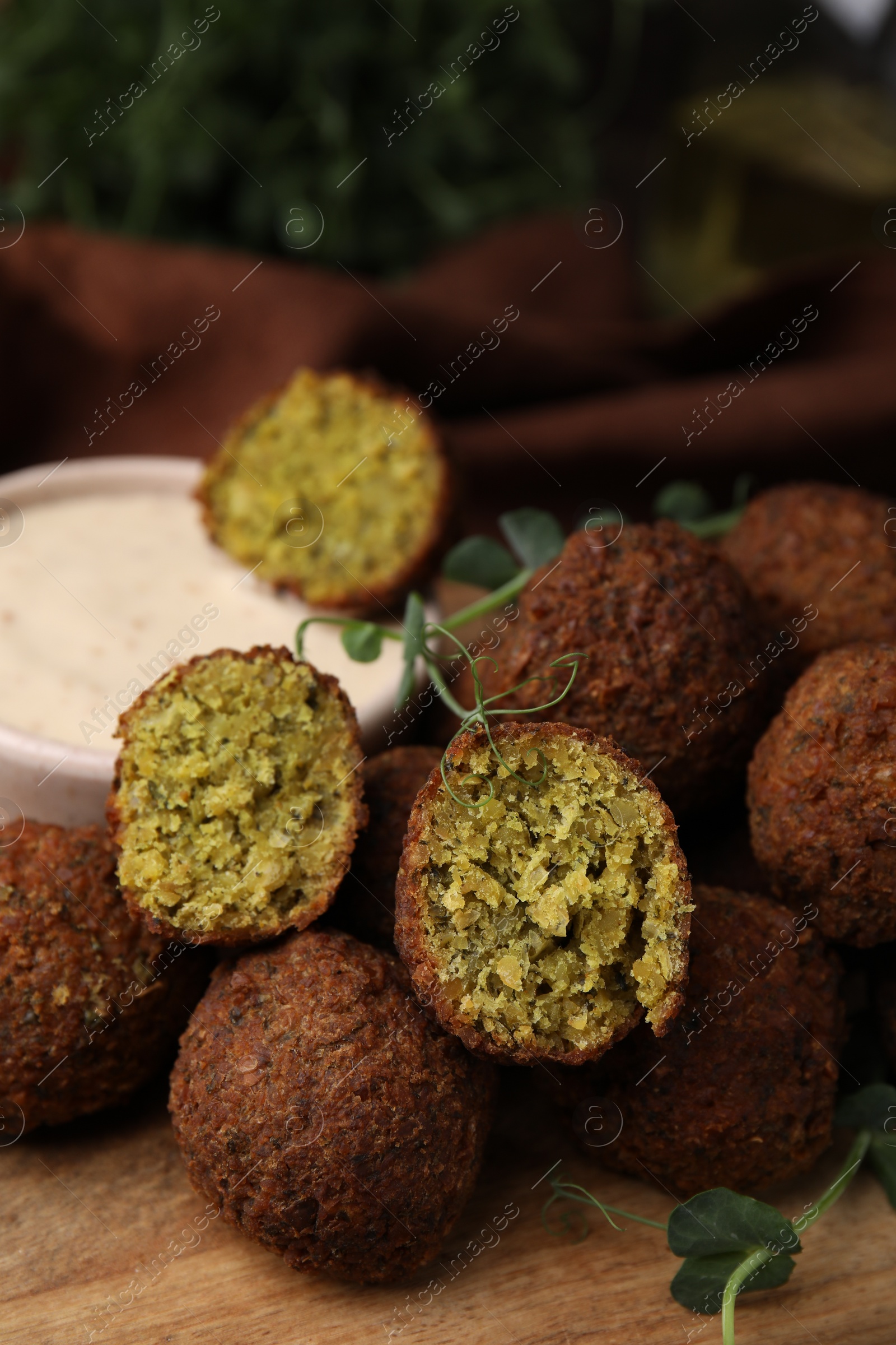 Photo of Delicious falafel balls and sauce on wooden board