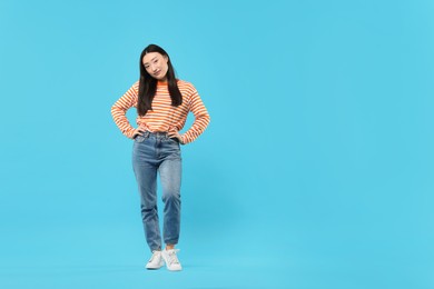 Full length portrait of cute woman on light blue background. Space for text