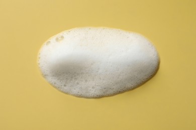 Photo of Foam with many bubbles on yellow background, above view
